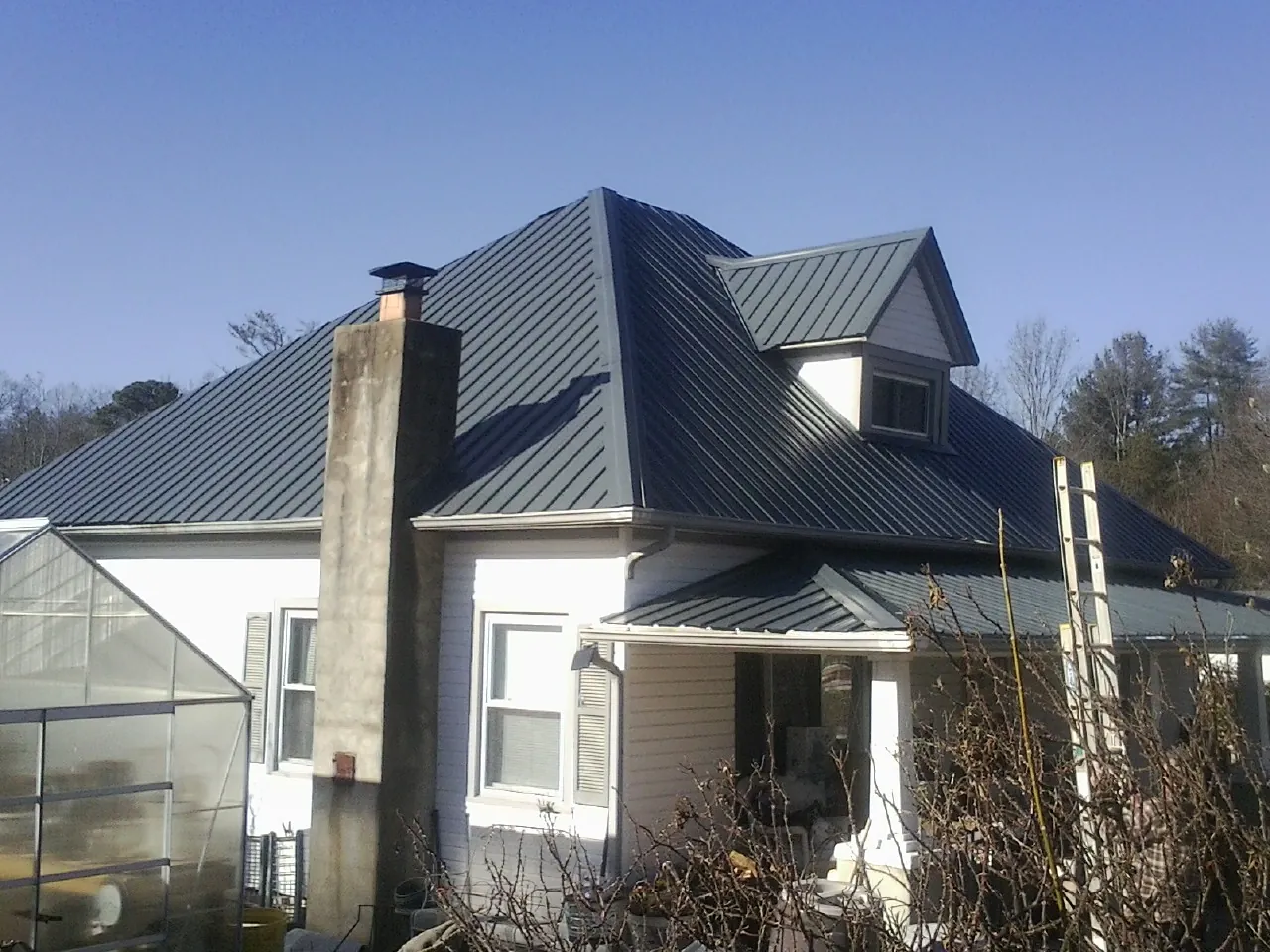 Dark blue standing seam metal roof on a white farmhouse with dormer — Slate & Tile Roof Repair by Roofing Brothers in Ramah