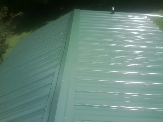 New green metal panels meeting at the ridge of a roof — Flat Roof Repair work by our crew in Ramah