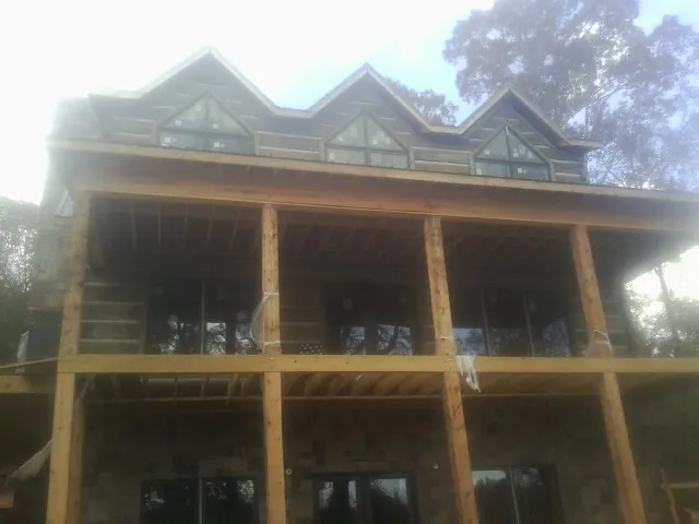 Dormers and porch framing on a large log home under construction — Roof Coating work by our crew in Ramah