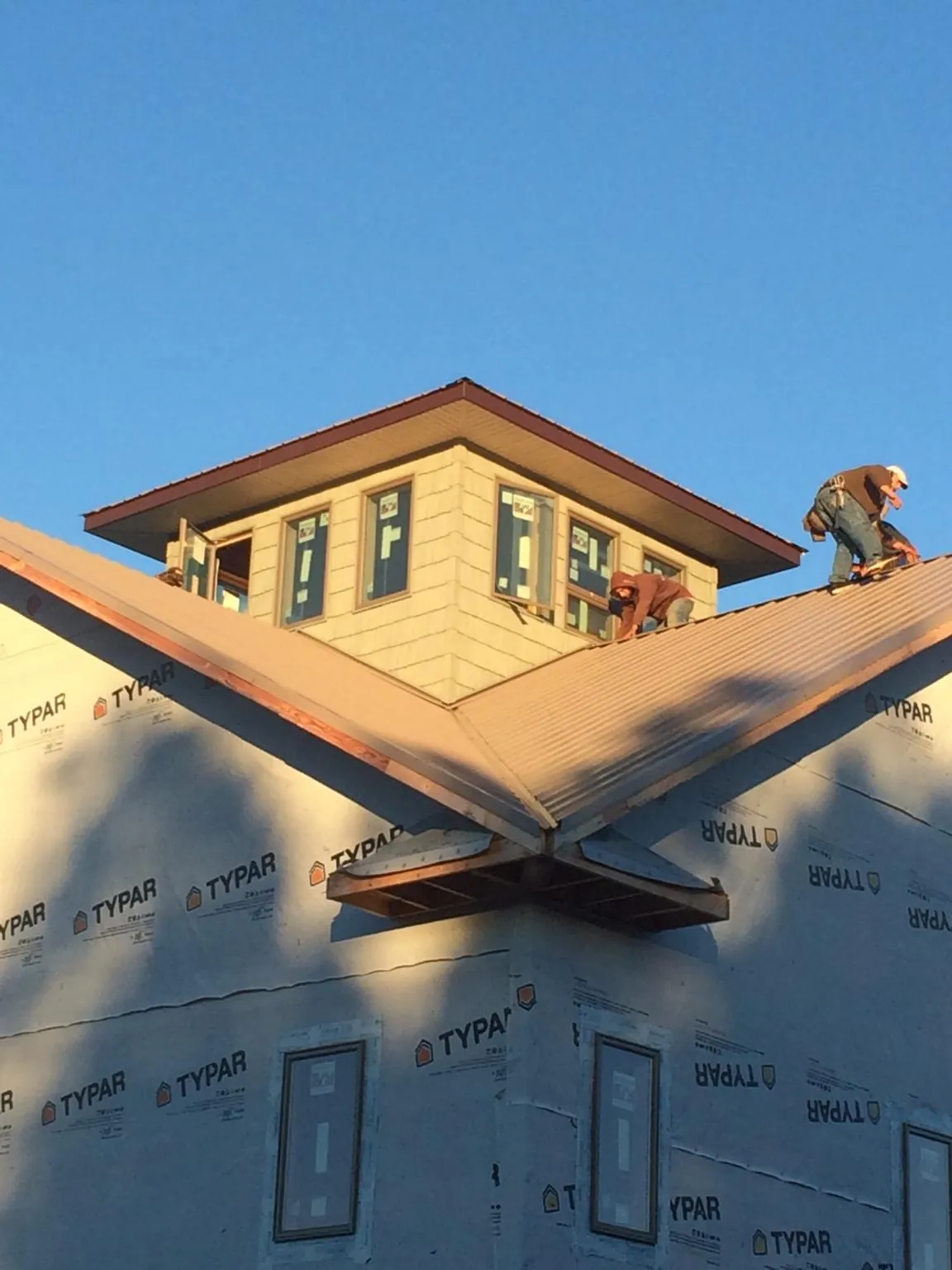 Roofers working around a rooftop cupola on a new metal roof at sunset — Roof Waterproofing in Ramah by Roofing Brothers
